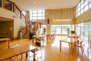 木製家具が配置された広々とした共用ロビー。採光が良く温かみのある空間